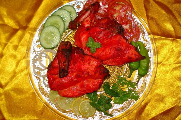 Tandoori chicken with cucumber slices and herbs on a plate